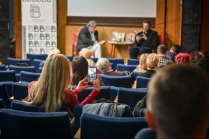 kobieta z widowni robiąca zdjęcie telefonem