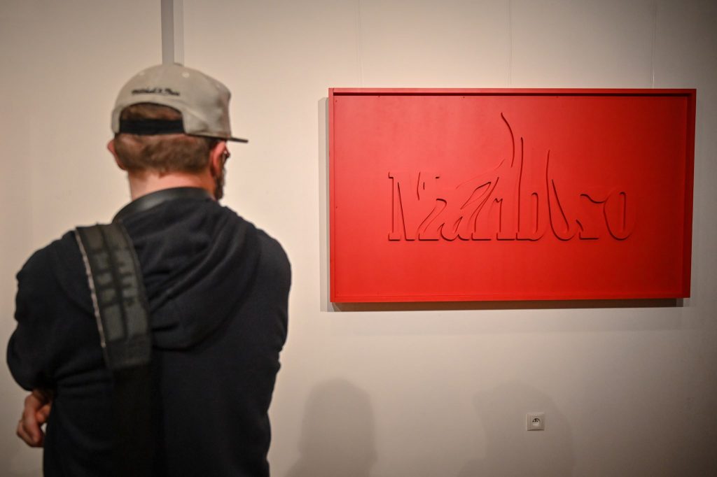 mężczyzna oglądający obraz przedstawiający zmodyfikowany znak graficzny marki Marlboro