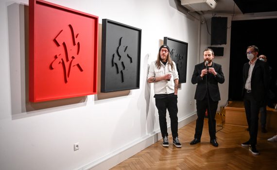 Łukasz Gawron Jan Sętowski i Robert Jasiak stojący przed wystawionymi pracami artystycznymi w galerii sztuki