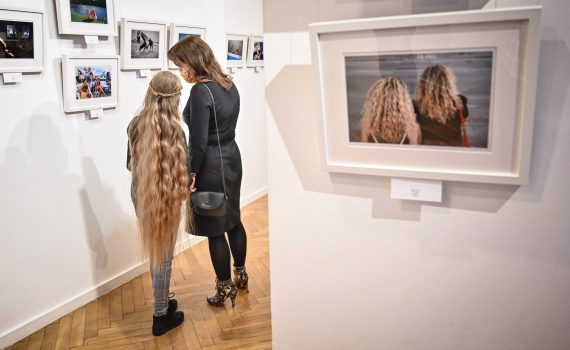 kobieta z dziewczynką o długich blond włosach oglądające wystawę fotografii