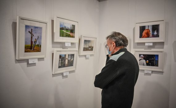 starszy mężczyzna oglądający wystawę fotografii