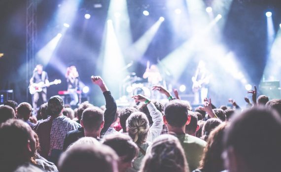 koncert muzyczny publiczność pod sceną na scenie zespół muzyczny reflektory rozświetlające scenę