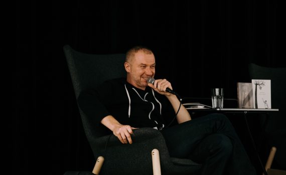 uśmiechnięty Łukasz Jarosz trzymający mikrofon przy ustach