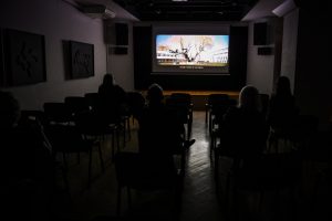 publiczność pogrążona w ciemności oglądająca film wyświetlany na ekranie