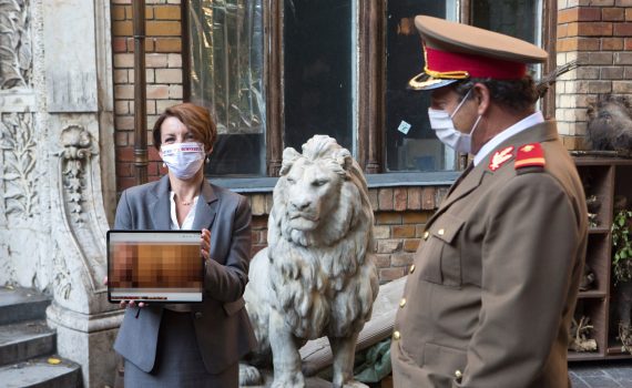 Niefortunny numerek lub szalone porno film w reżyserii Radu Jude kadr kobieta trzymająca tablet z ocenzurowanym materiałem wideo mężczyzna w mundurze po prawej w tle kamienny posąg z lwem