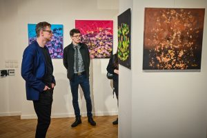 dwóch mężczyzn oglądających wystawę obrazów w galerii sztuki