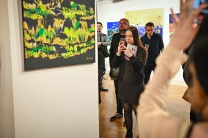 publiczność oglądająca wystawę w galerii sztuki kobieta robiąca zdjęcie obrazu