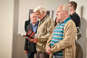 mężczyzna przeglądający katalog wystawy podczas wenisażu wystawy