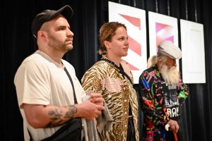 trzy osoby zgromadzone na wernisażu wystawy