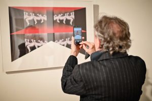 mężczyzna wykonujący fotografię obrazu w galerii sztuki