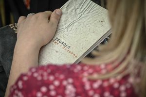 kobieta trzymająca książkę Marcina Zegadło zatytułowaną Marte i Ozdobne, widoczny fragment okładki książki z nazwiskiem autora i niepełnym tutułem książki
