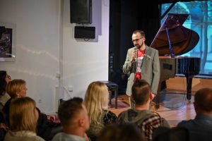 dyrektor Ośrodka Promocji Kultury Gaude Mater w Częstochowie witający publiczność podczas wydarzenia kulturalnego w instytucji