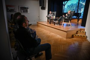 prowadzący i gość rozmawiający podczas spotkania z publicznością zgromadzoną pod sceną