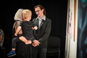 Emilia Dudziec z dzieckiem na rękach oraz Aleksander Szumlas rozmawiający ze sobą podczas wernisażu