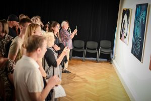 publiczność oglądająca obrazy na wernisażu wystawy w galerii sztuki