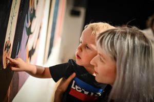 dziecko na rękach wskazujące palcem na fragment obrazu