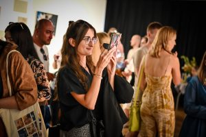 kobieta robiąca smarfonem zdjęcie obrazom podczas wystawy w galerii sztuki