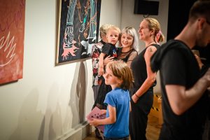 Emilia Dudziec z dzieckiem na ręku oraz Agata Wierny oglądające obrazy na wystawie