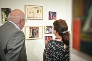 mężczyzna i kobieta odwróceni tyłem oglądający obrazy podczas wystawy artystycznej w galerii sztuki