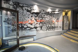 drzwi wejściowe do Ośrodka Promocji Kultury Gaude Mater zawierajace napis z nazwą instytucji oraz fragment muralu Bartłomieja Stypki