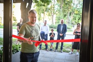 Bartłomiej Stypka przecinający czerwoną wstęgę podczas odsłonięcia swojego muralu w Ośrodku Promocji Kultury Gaude Mater w Częstochowie