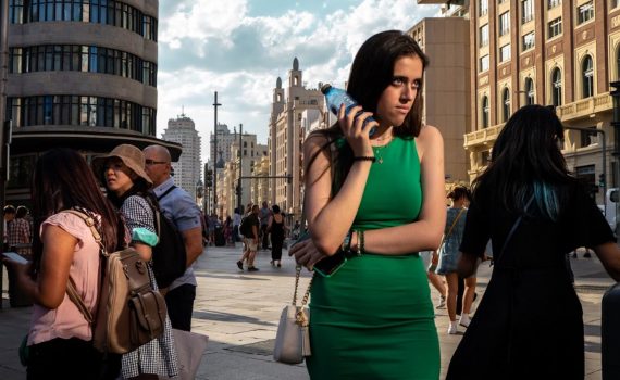 kobieta w zielonej sukience z butelką wody przy głowie na ulicy w tle ludzie i budynki fotografia Andresa Ramosa Palaciosa