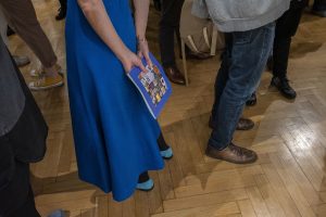 kobieta trzymająca za plecami katalog wystawy