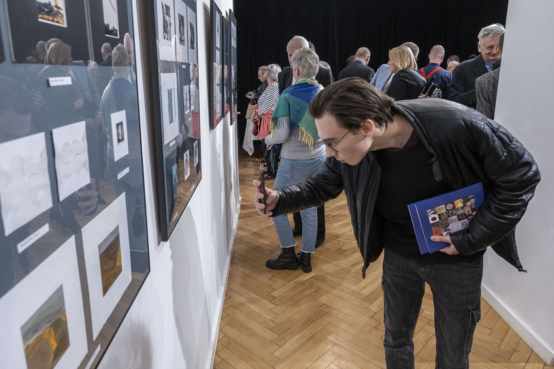 mężczyzna wykonujący fotografię ekspozycji podczas wernisażu wystawy