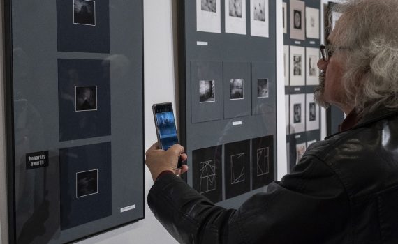 mężczyzna wykonujący zdjęcie ekspozycji prac w galerii sztuki