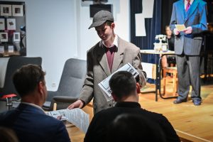 młody aktor rozdający publiczności gazetę podczas spektaklu