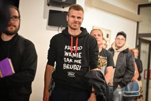 mężczyzna w bluzie z napisem „Kartkowanie rąk nie brudzi”