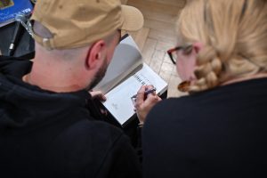 Jakub Żulczyk wpisujący autograf do swojej książki