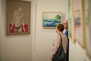 kobieta i mężczyzna oglądający obrazy podczas wystawy sztuki
