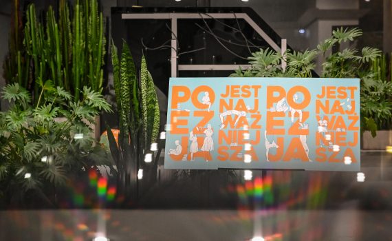 zdjęcie planszy z napisem "poezja jest najważniejsza" na tle roślin w holu ośrodka promocji kultury gaude mater w częstochowie