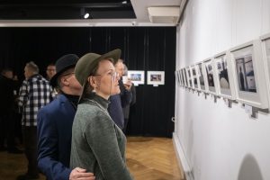 kobieta w kapeluszu przyglądająca się wystawie fotografii