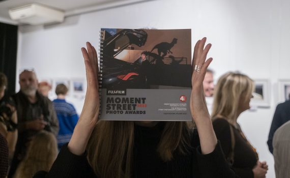 kobieta zasłaniająca twarz katalogiem wystawy fujifilm moment street photo awards 2022