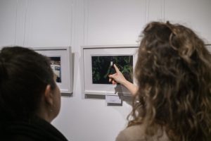 kobieta pokazująca palcem wskazującym na fotografię zawieszoną w galerii sztuki
