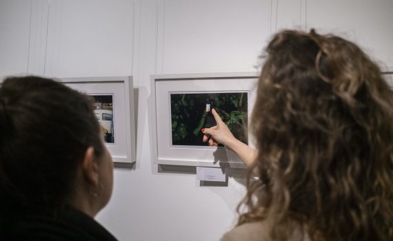 kobieta pokazująca palcem wskazującym na fotografię zawieszoną w galerii sztuki