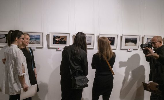 kobiety pozujące do zdjęcia przed fotografem podczas wernisażu wystawy