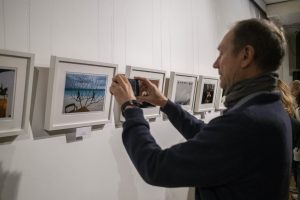 mężczyzna wykonujący fotografię ekspozycji w galerii sztuki