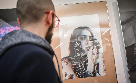 obraz na wystawie przedstawiający młodą kobietę z narysowanym na niej zarysem szkieletu