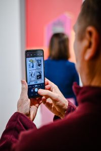 mężczyzna wykonujący zdjęcie obrazowi podczas wystawy sztuki