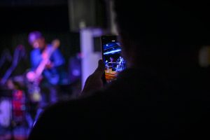 osoba wykonująca fotografię telefonem podczas koncertu